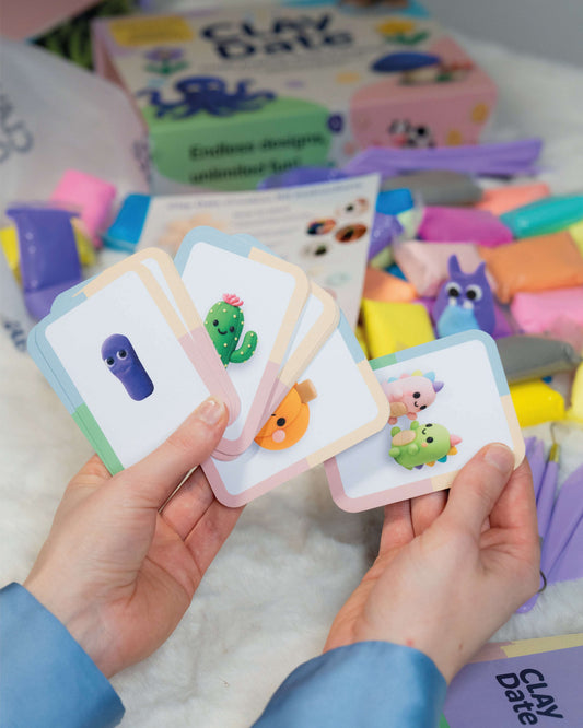 Colorful clay modeling tools and cards held by a person with a Clay Date™ Kit