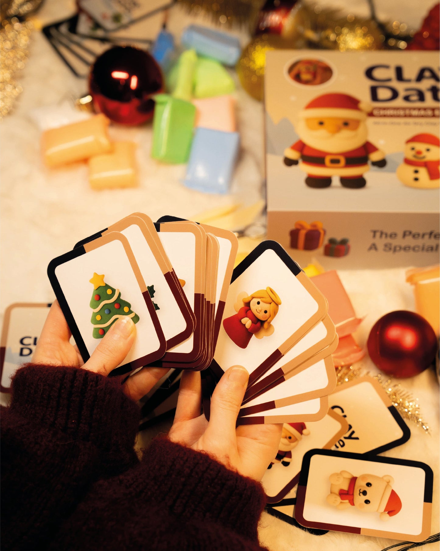 Hand holding Christmas-themed inspiration cards with festive decorations in the background