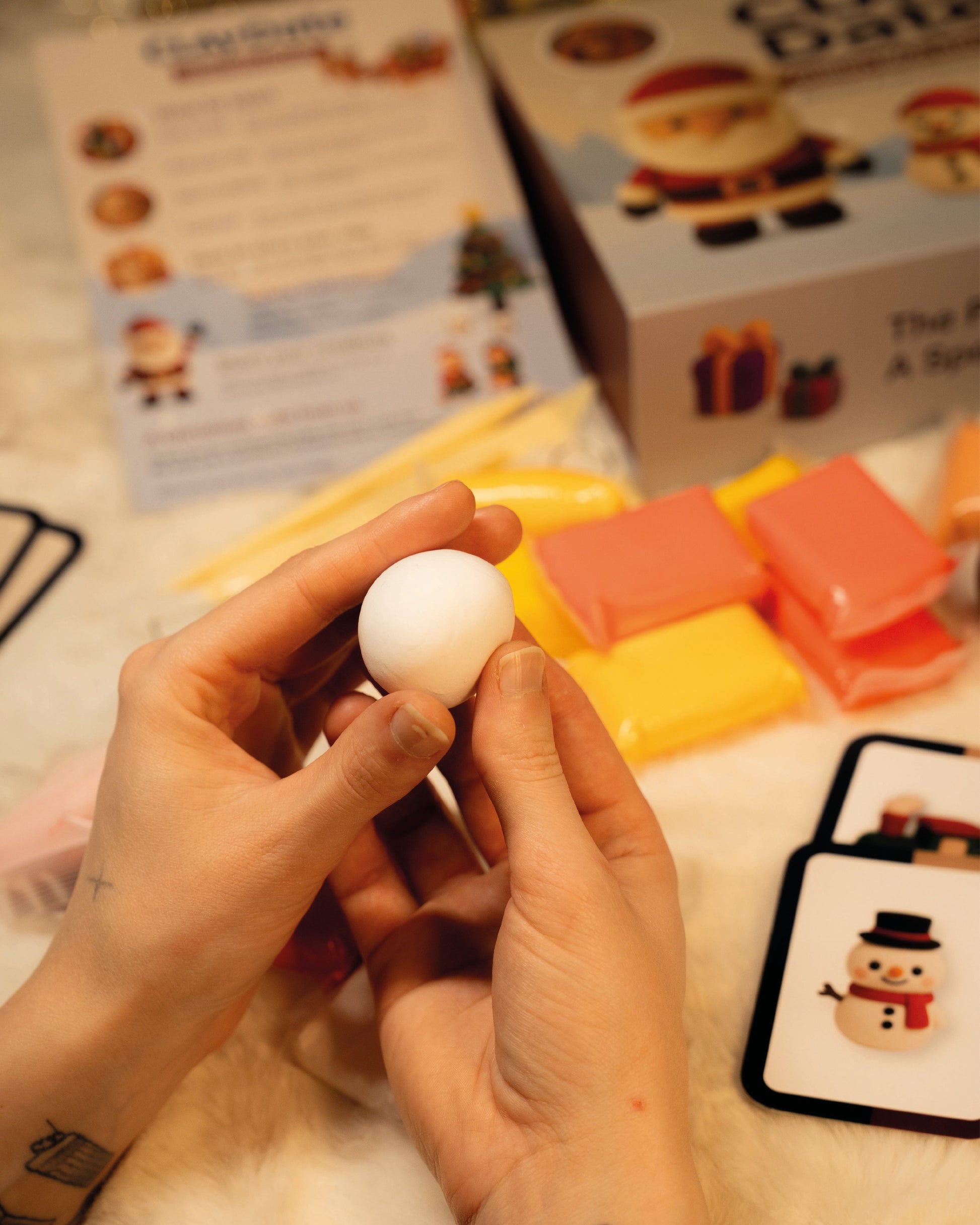 Person holding a small white object with a box and materials in the background