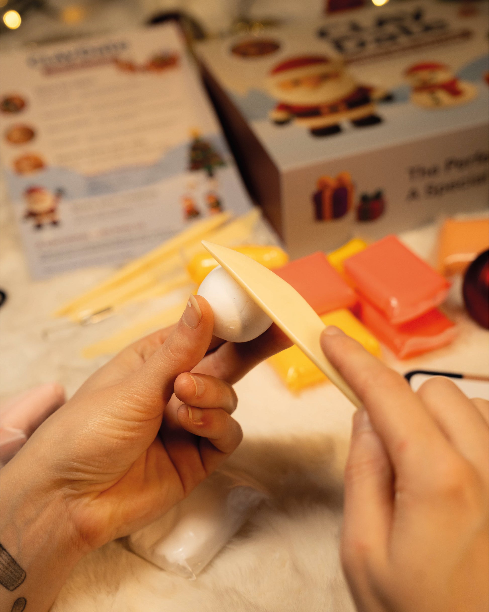 Hands holding a small object with a blurred background featuring a box and paper.