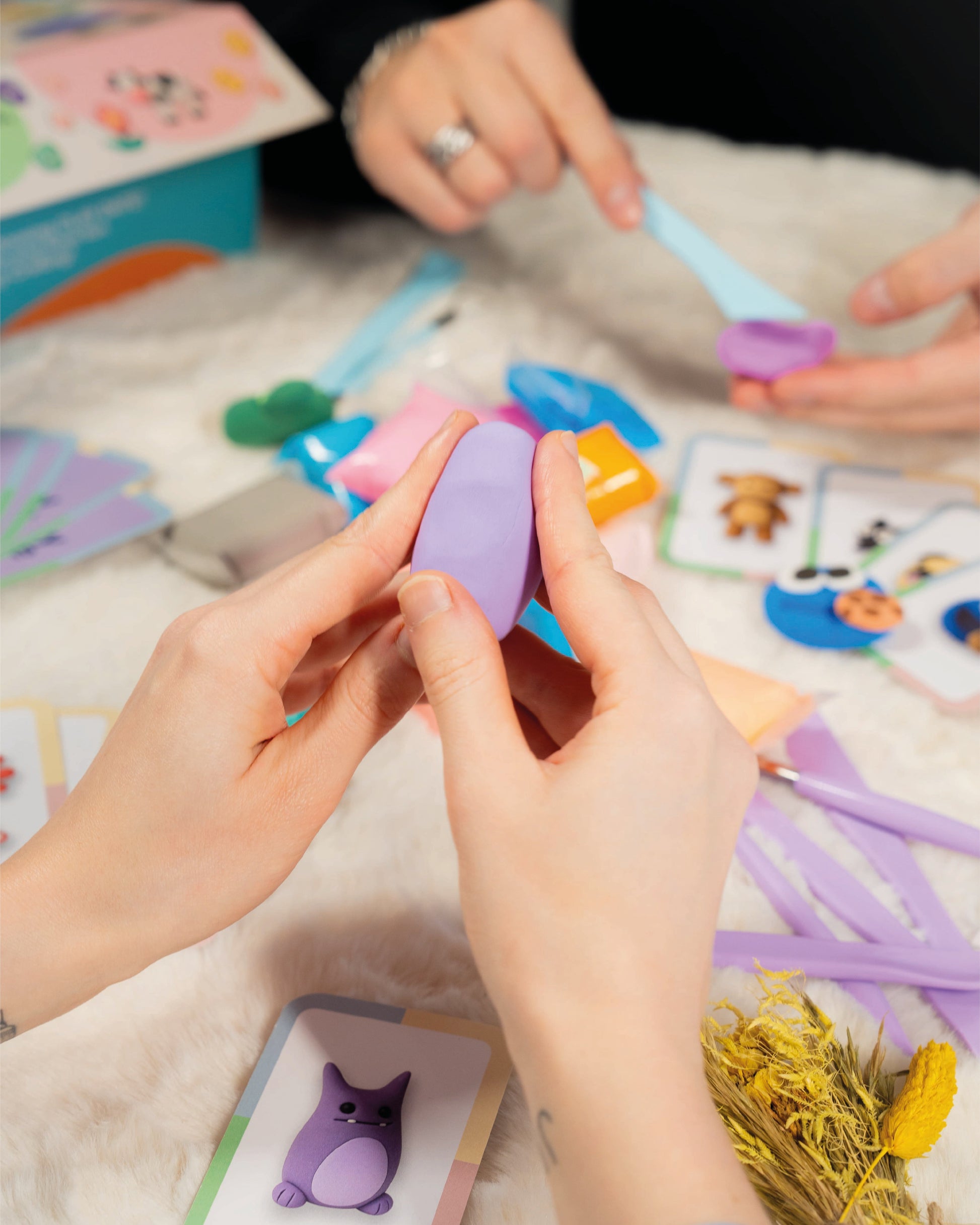 Person holding a purple egg with colorful tools and cards on a textured surface