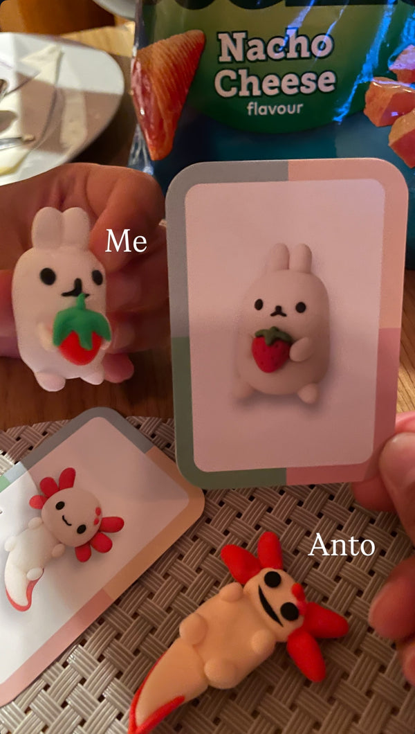 Two clay figurines labeled 'Me' and 'Anto' with a packet of nacho cheese flavor in the background.