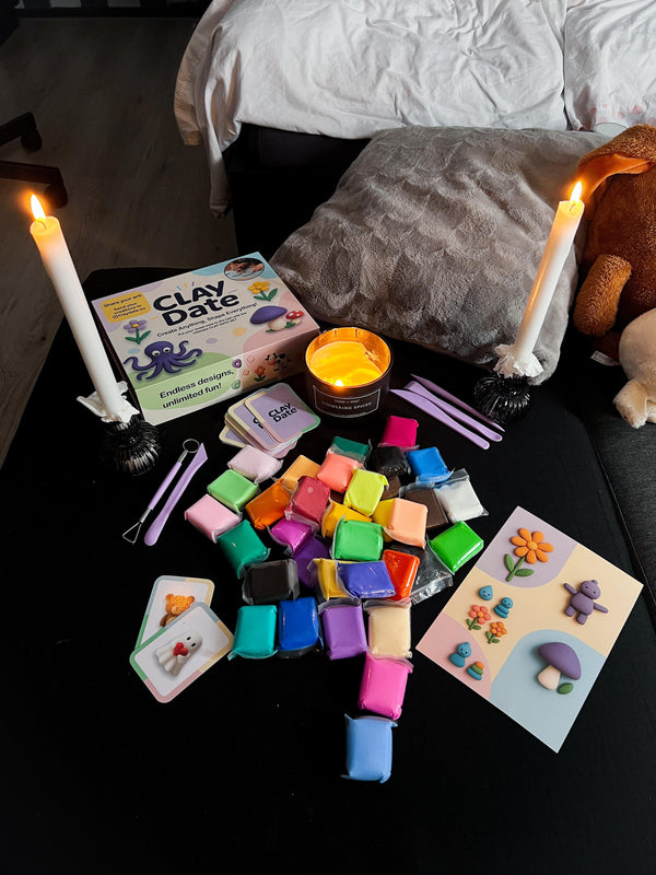Colorful clay blocks on a table with candles and a book titled 'Clay Date' in a cozy indoor setting.