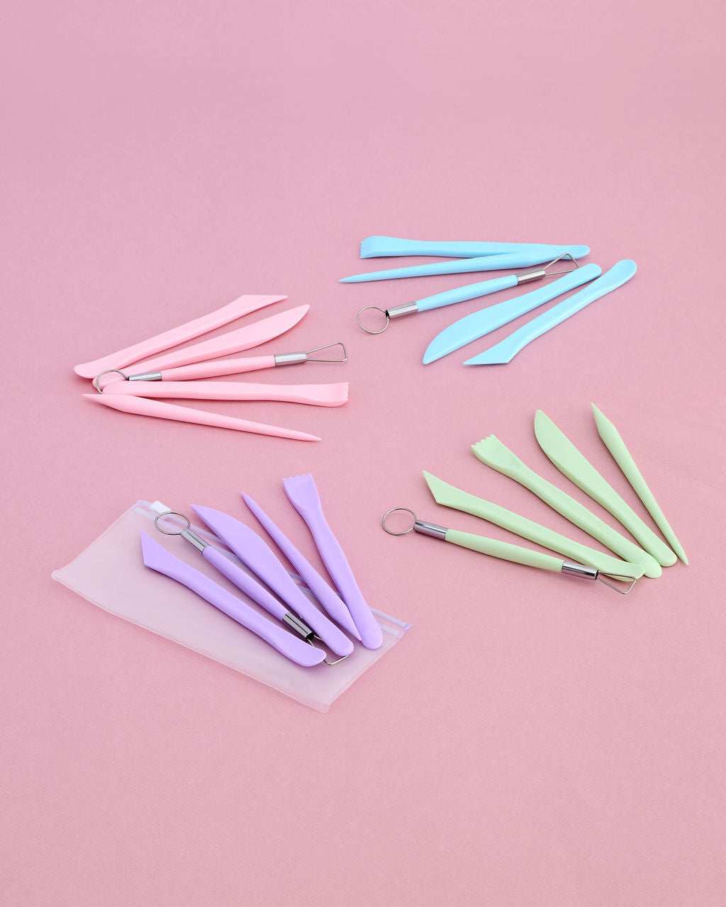 A set of pastel-colored sculpting tools arranged on a solid pink background.