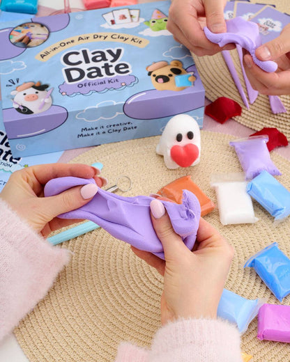 A person's hands stretching a purple clay figure over a woven beige mat, with a blue and purple 'Clay Date Official Kit' box in the background.