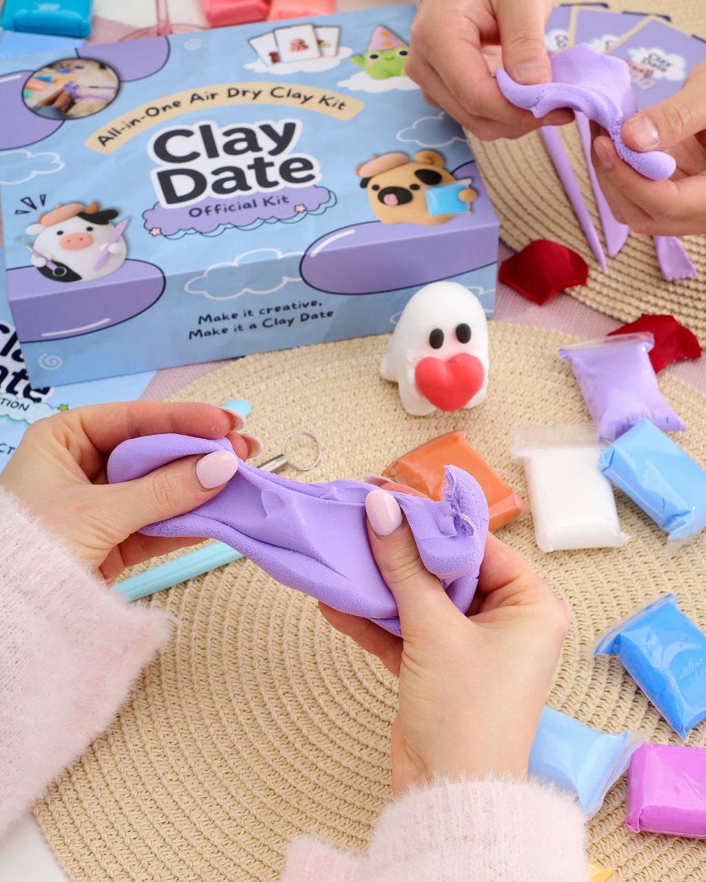 Two hands holding finished clay creations made with the Clay Date New Official Kit