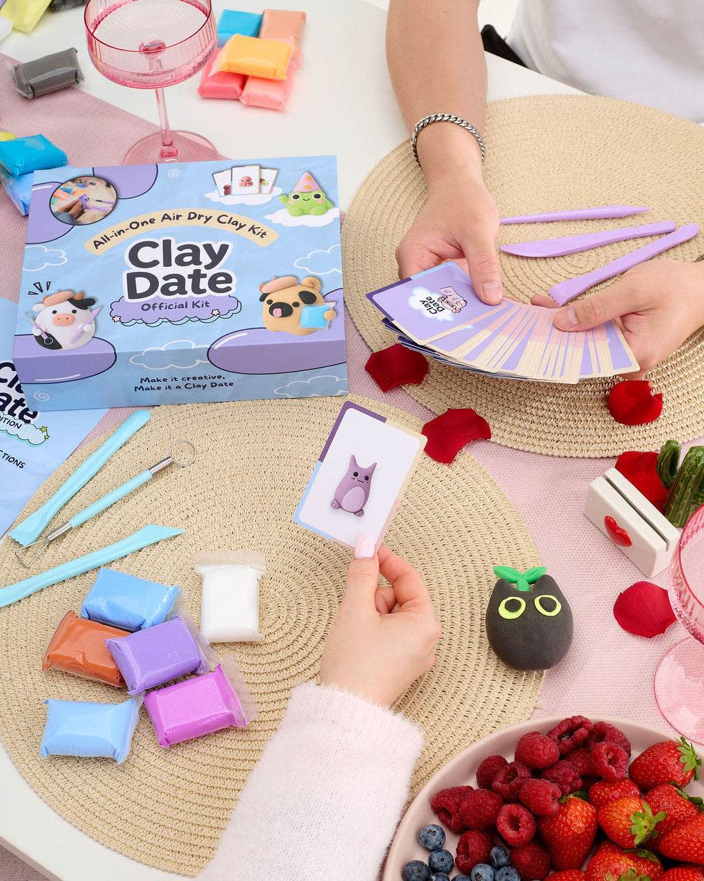 Hand holding an inspiration card next to a completed clay creation from the Clay Date New Official Kit